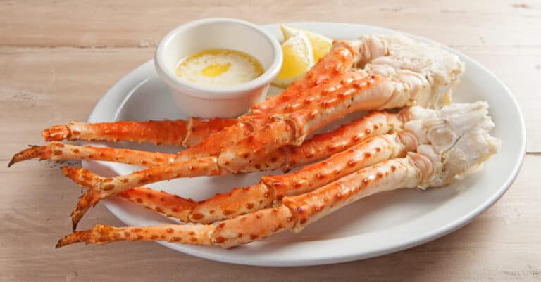 A plate filled with steamed snow crab legs served with butter and lemon