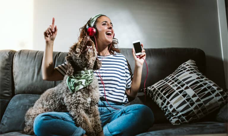 A woman with headphones singing with her dog