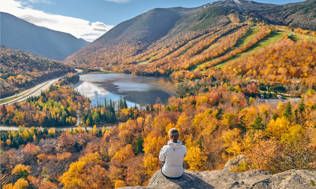 A photo of Echo Lake State park and a woman seated on a rock. 