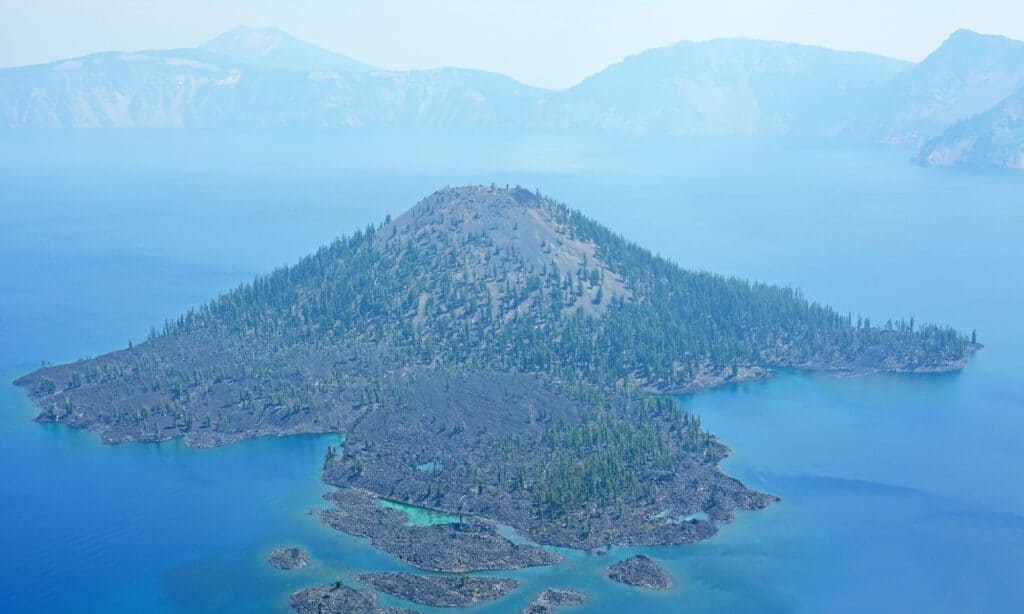 An aerial view of Crater Lake, a caldera lake in Oregon, surrounded by cliffs and forest. 