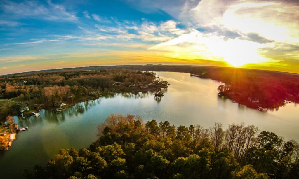 A photo of a summer sunset over Lake Wylie in South Carolina, USA with rippling waves and cypress trees along the shore. 