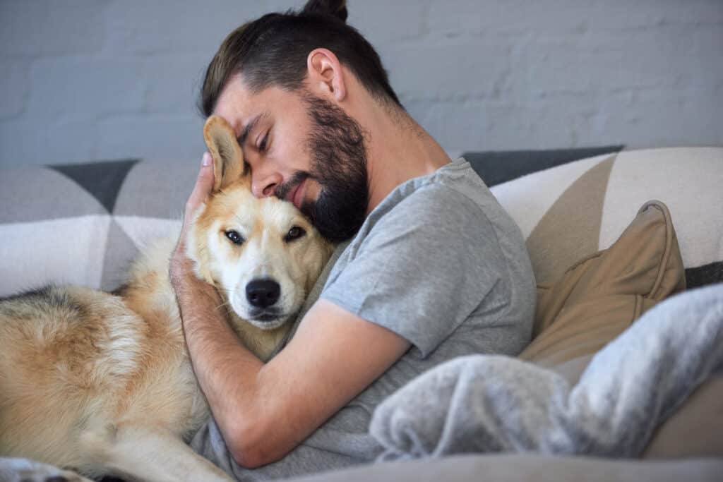 man cuddling dog