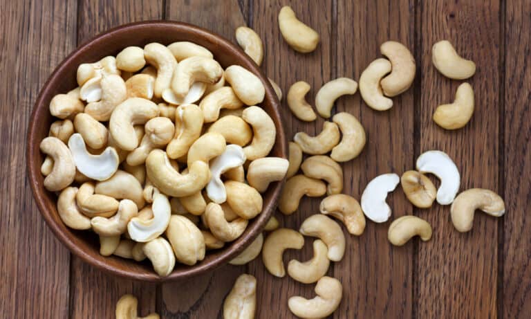 Overflowing bowl of halved cashew nuts