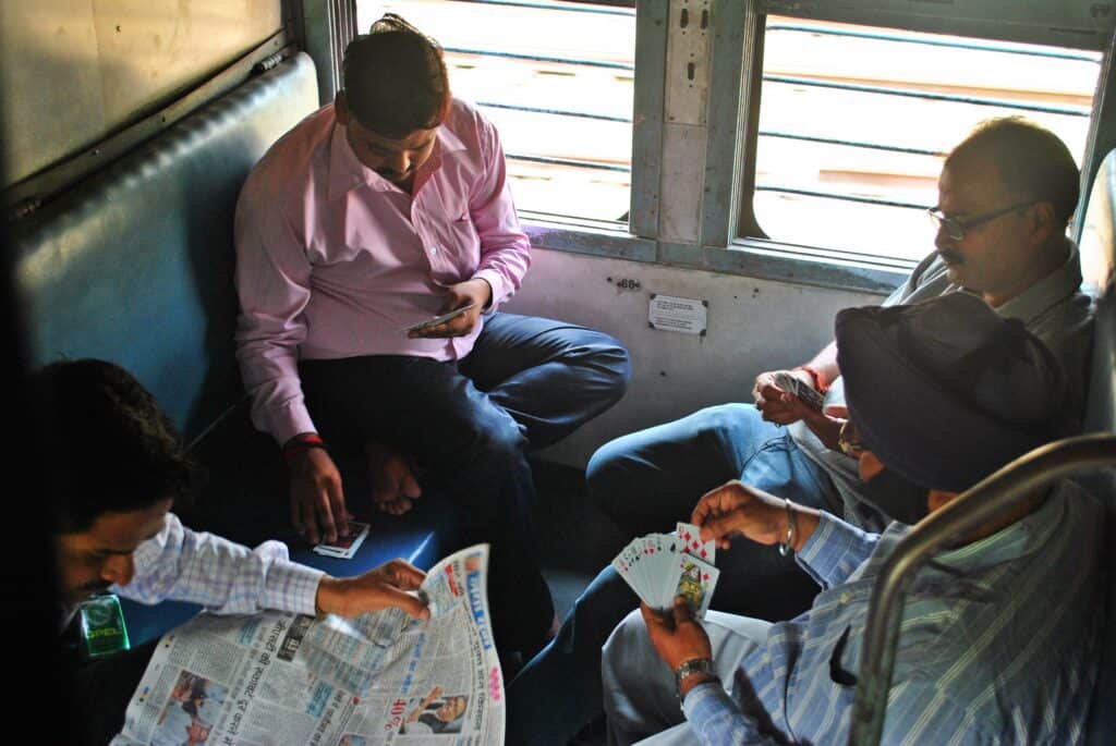 four passengers in a train car playing cards with each other