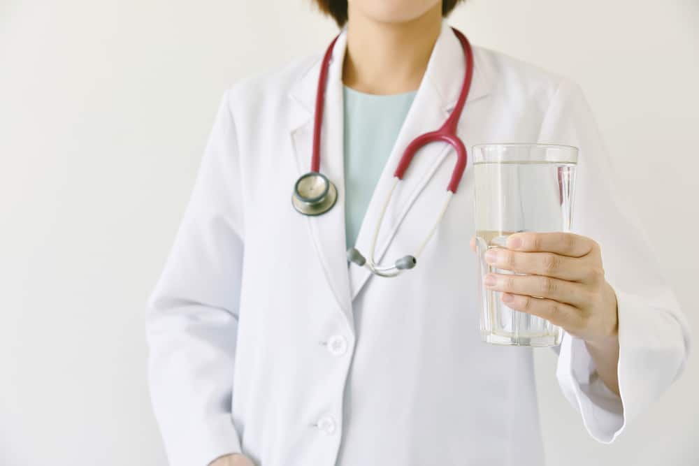 Doctor holding a glass of clear fresh water, Doctor recommend drinking healthy water.