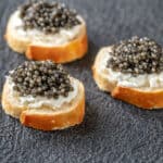 Baguette slices with cream cheese and black caviar.