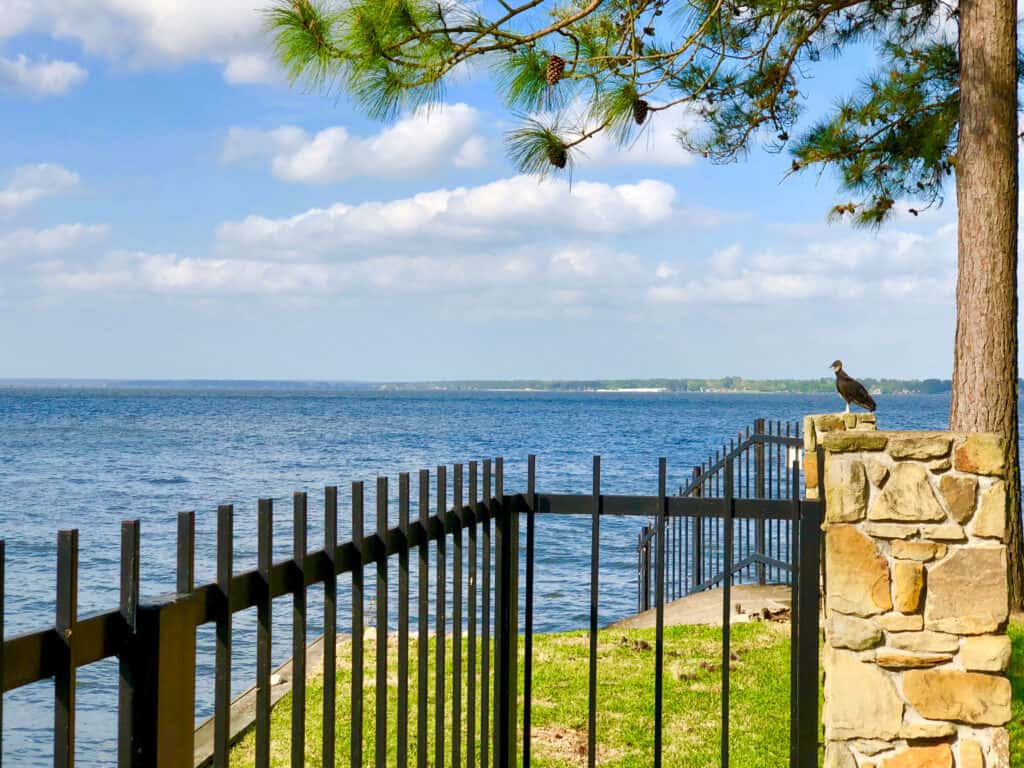 View of Lake Conroe, Texas through wrought iron and stone fence