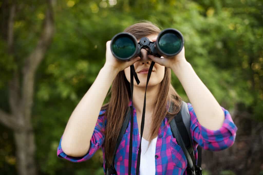Young woman with binoculars in the woods