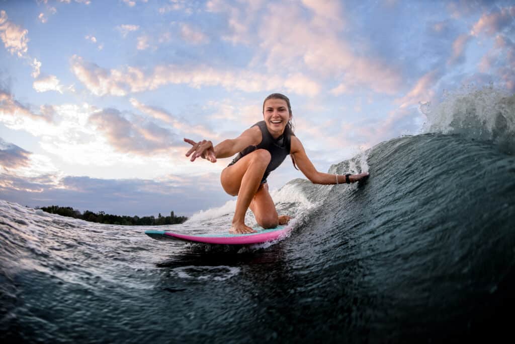 Young woman surfing on pink surfboard