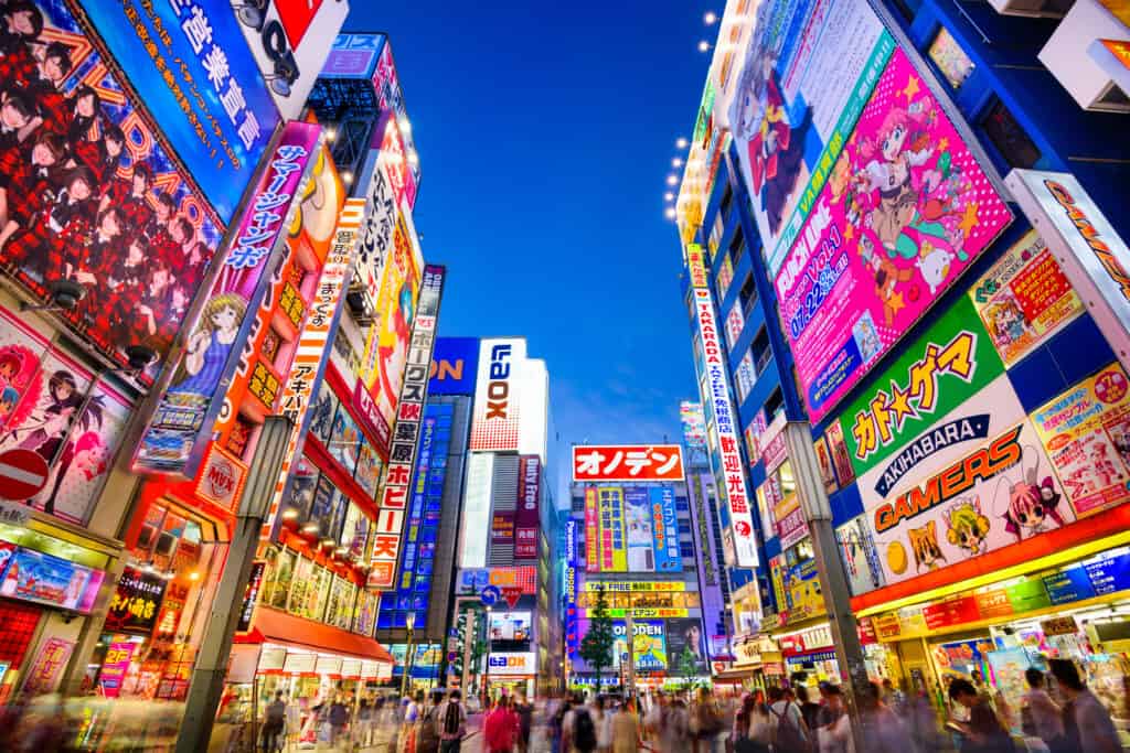 TOKYO, JAPAN - AUGUST 1, 2015: Crowds pass below colorful signs in Akihabara. The historic electronics district has evolved into a shopping area for video games, anime, manga, and computer goods.