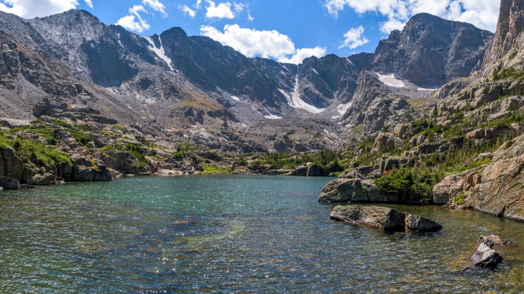 Lake of Glass - A panoramic view of clear and colorful Lake of Glass surrounded by rugged high peaks of Continental Divide on a sunny Summer day. Rocky Mountain National Park, Colorado, USA.