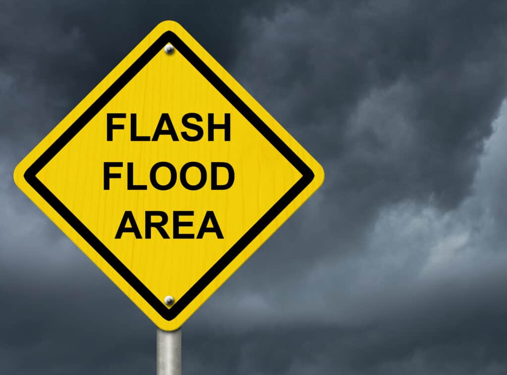 A flash flood area sign against a stormy sky