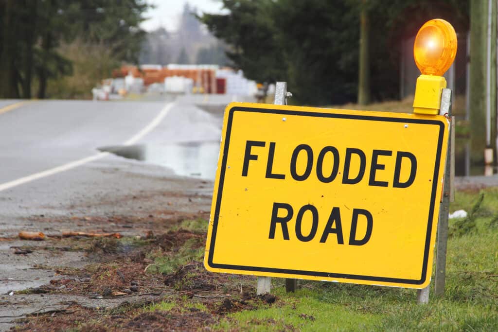 Yellow flooded road sign on the side of a road