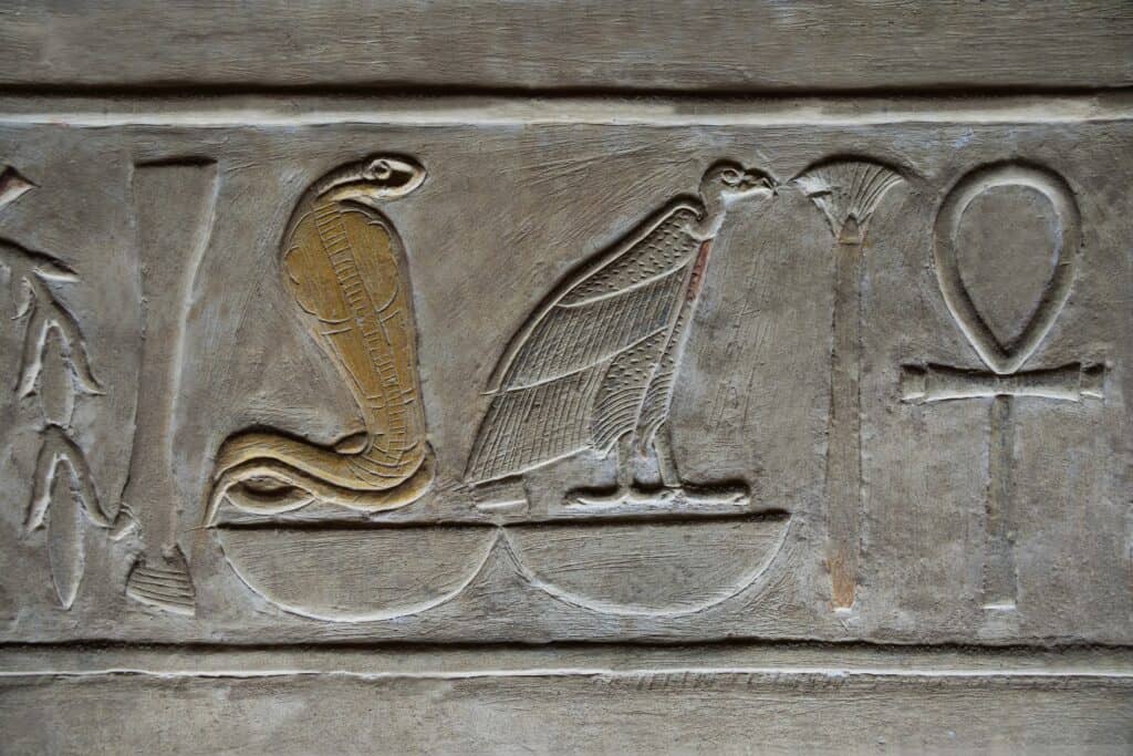 Hieroglyphics depicting a rearing Egyptian cobra, a vulture, and an ankh (symbol for eternal life.