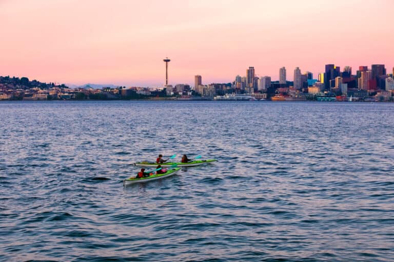 Kayaks in Puget Sound waters with skyline and cityscape of Seattle, WA in background.