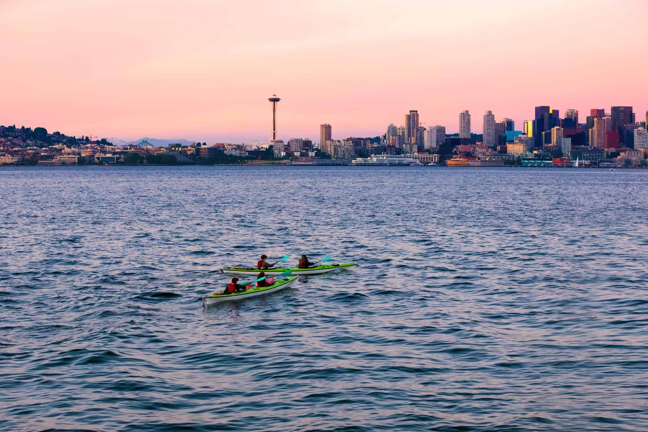 Kayaks in Puget Sound waters with skyline and cityscape of Seattle, WA in background.