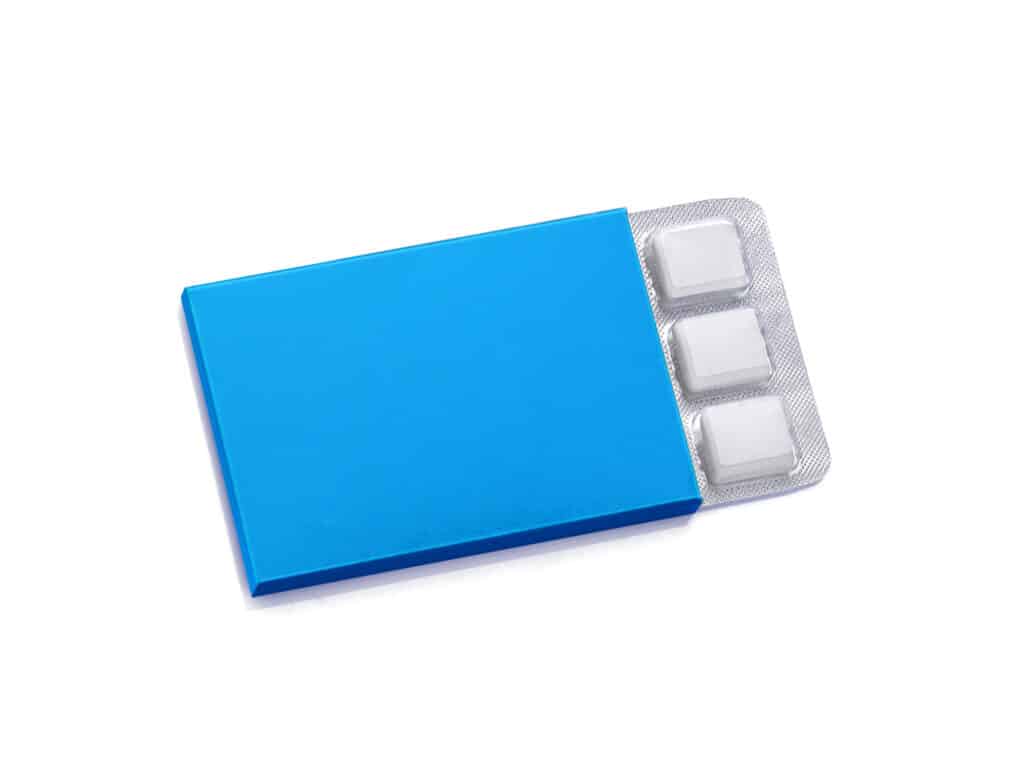 generic package of chewing gum. The  package is plain blue, absent of  writing or words. Three  rectanglular pieces of gum encased in clear plastic (top) and silver foil (bottom) are sticking out of the open rectangular pack, which appears to have nine more pieces inside. 