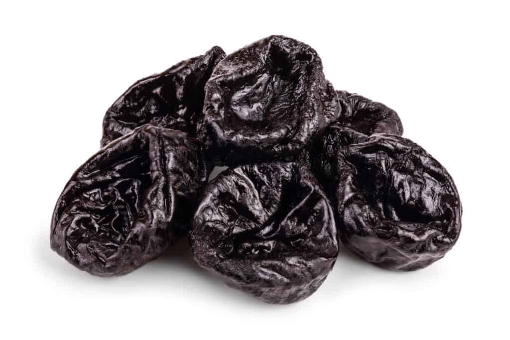 seven dark brown prunes isolated on a white background