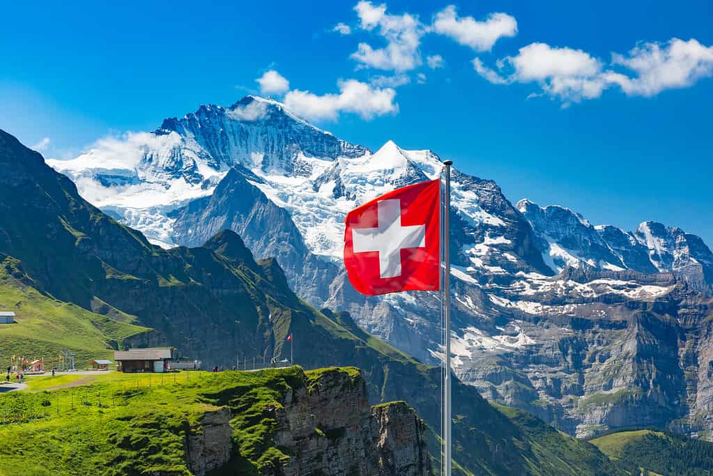 Swiss flag waving on a mountain peak in Switzerland