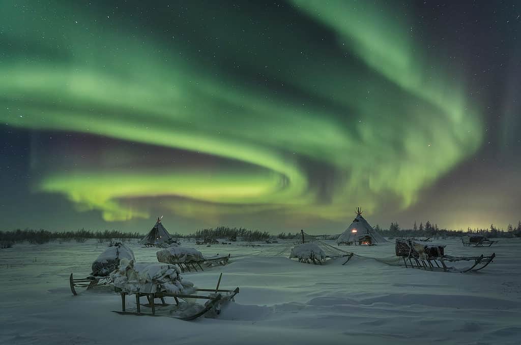 Frosty clear night and bright Aurora Borealis in the camp of reindeer herders on the Yamal Peninsula. Russia.
