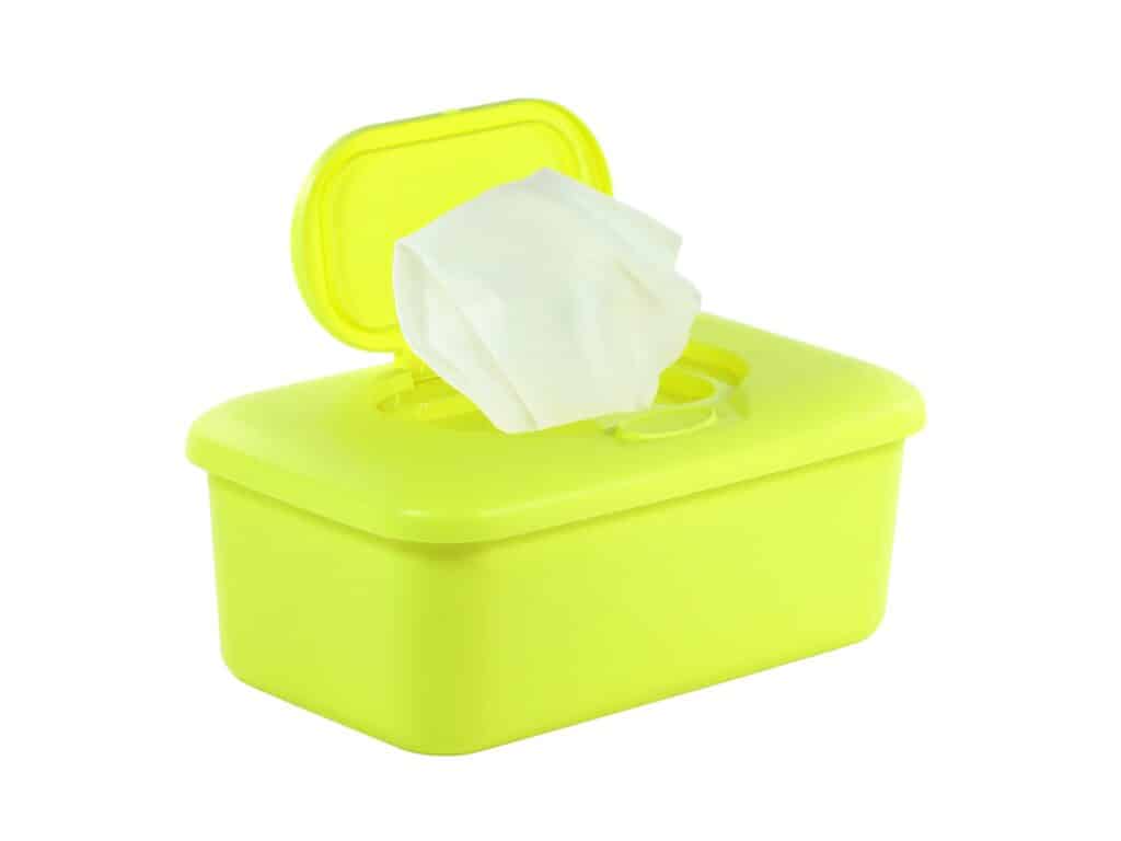 A neon yellow plastic pop-up container of baby wipes with a white baby wipe at the ready. White background. 