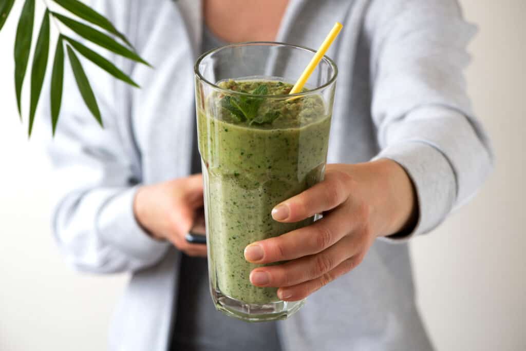 woman holding green smoothie