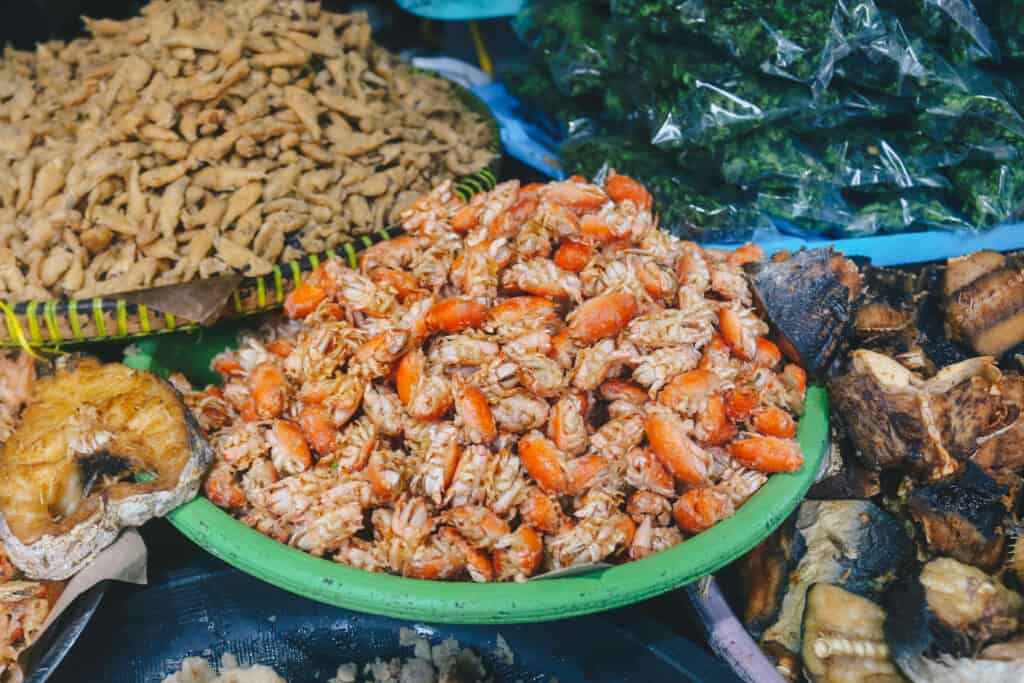 The center and focus of tefrme is a pistachio green plastic (?) plate heaped with steamed sand fleas.The plate is surrounded by four other various vessels filed with four distinctly different foods, of tan, green, brown and gold.