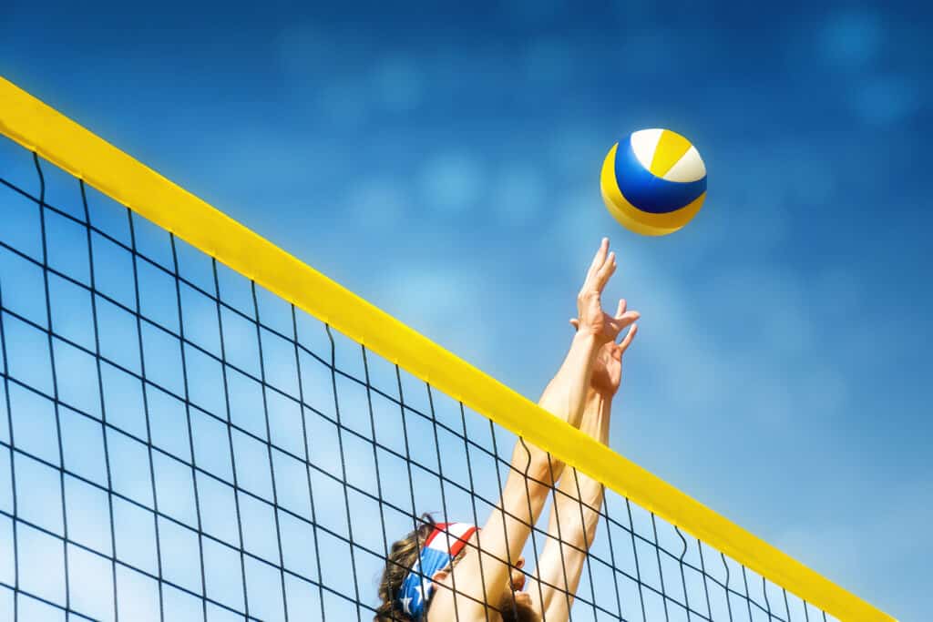 Hands reach over a net to hit a volleyball