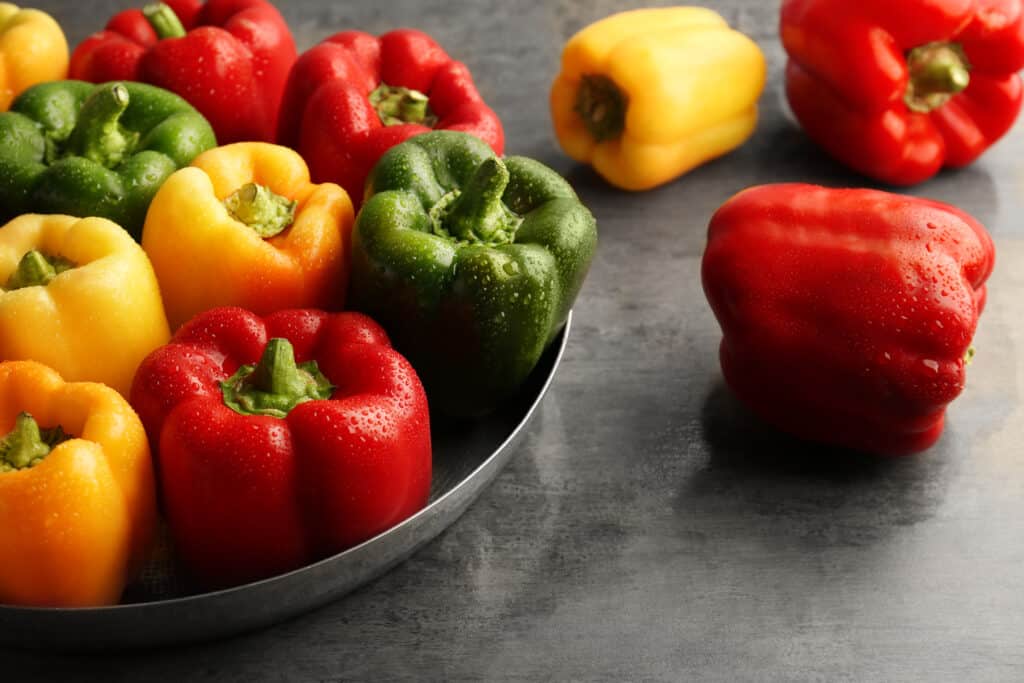 Red, green and yellow sweet bell peppers on table, close up