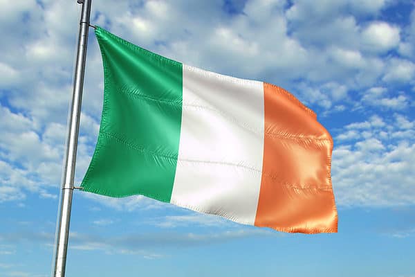 Ireland flag on flagpole waving cloudy sky background realistic 3d illustration