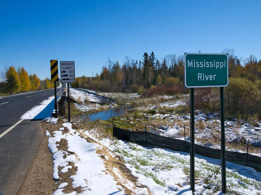 Mississippi River flowing north near its source at Itasca State Park in Minnesota. This sign is at the fifth highway bridge over the Mississippi River after an early autumn snowfall.