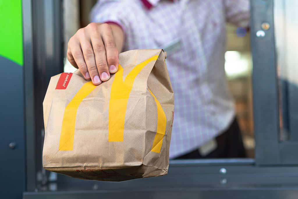 Man hands fast food bag out the drive-thru window