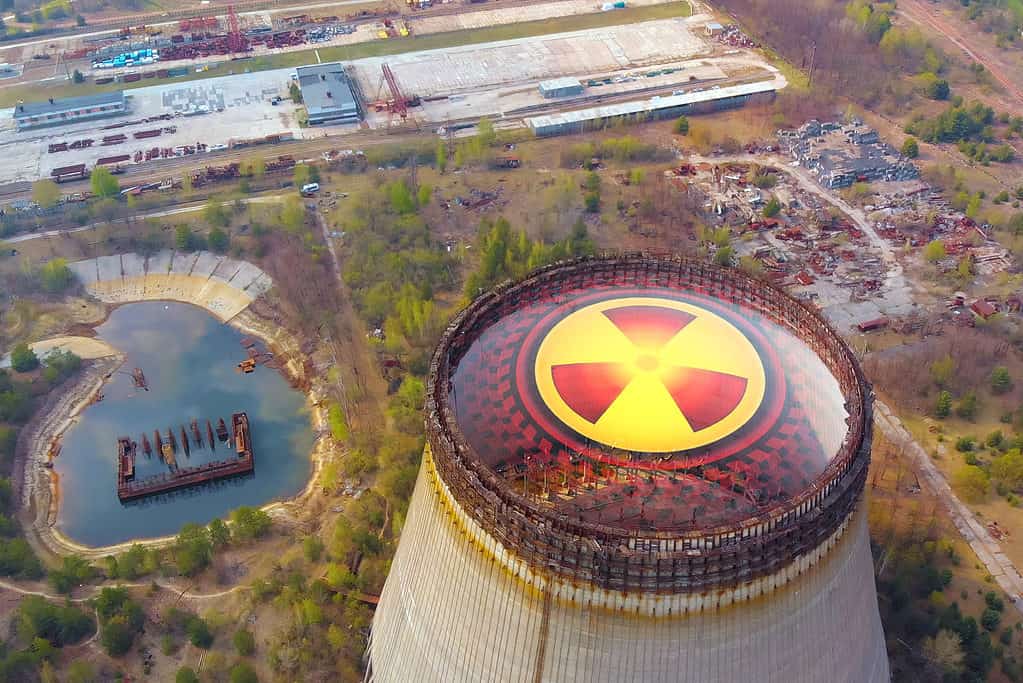 Chernobyl disaster. Radioactive zones near the reactor in Chernobyl. Sign of radiation on the background of the cooling tower in Chernobyl. Radiation contamination area near the Chernobyl reactor.