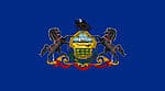 The flag of Pennsylvania consists of a blue field on which the state coat of arms is displayed. The state coat of arms consists of a shield between two horses with a bald eagle on top. It also features a plow, an olive branch with a cornstalk underneath the shield, and three golden sheaves of wheat.