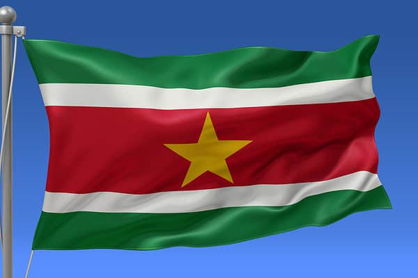 Suriname flag waving on the flagpole on a sky background