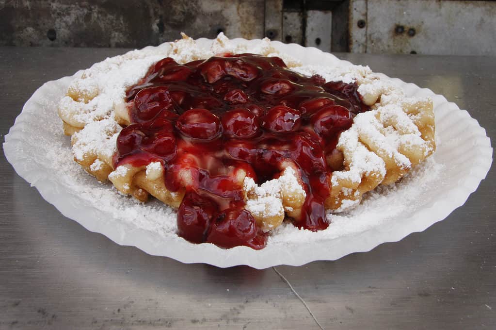 Funnel cake topped with sugar and cherry syrup