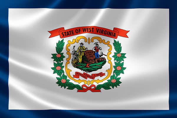 The flag of West Virginia consists a white field with a blue border surrounding the edges. The flag's center houses the state's coat of arms and on top of this seal is a ribbon with 