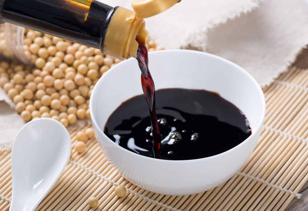 Pouring soy sauce into a white bowl