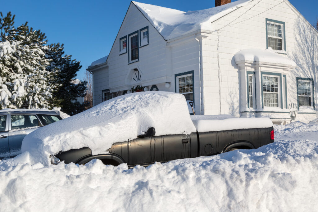Piles of snow bury a truck and home in a North American suburb.