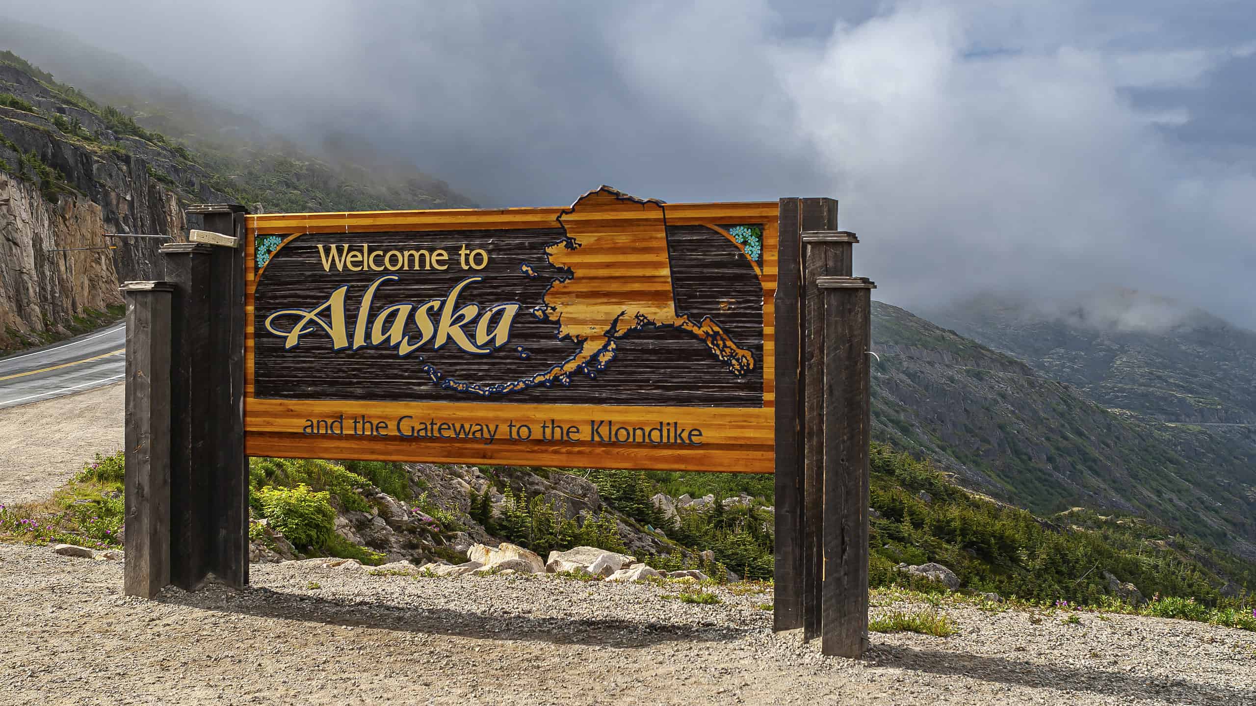 Skagway, Alaska, USA - July 20, 2011: Klondike highway to Canada. Colorful Welcome sign near the border. Cloudscape in back.