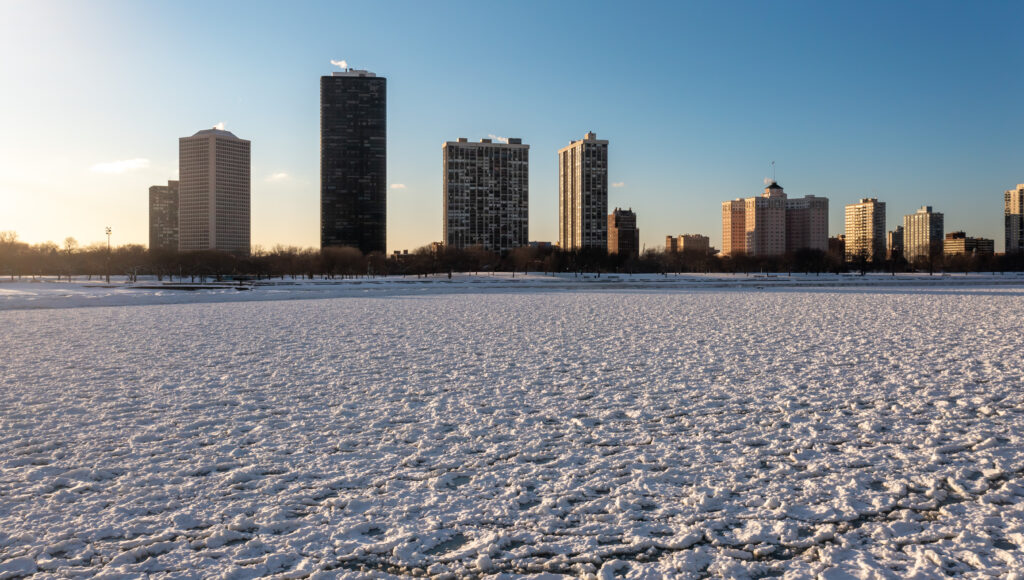 Skyline view of the Edgewater neighborhood residential highrise buildings from the frozen water of Lake Michigan near Foster beach with the lakefront covered in snow.