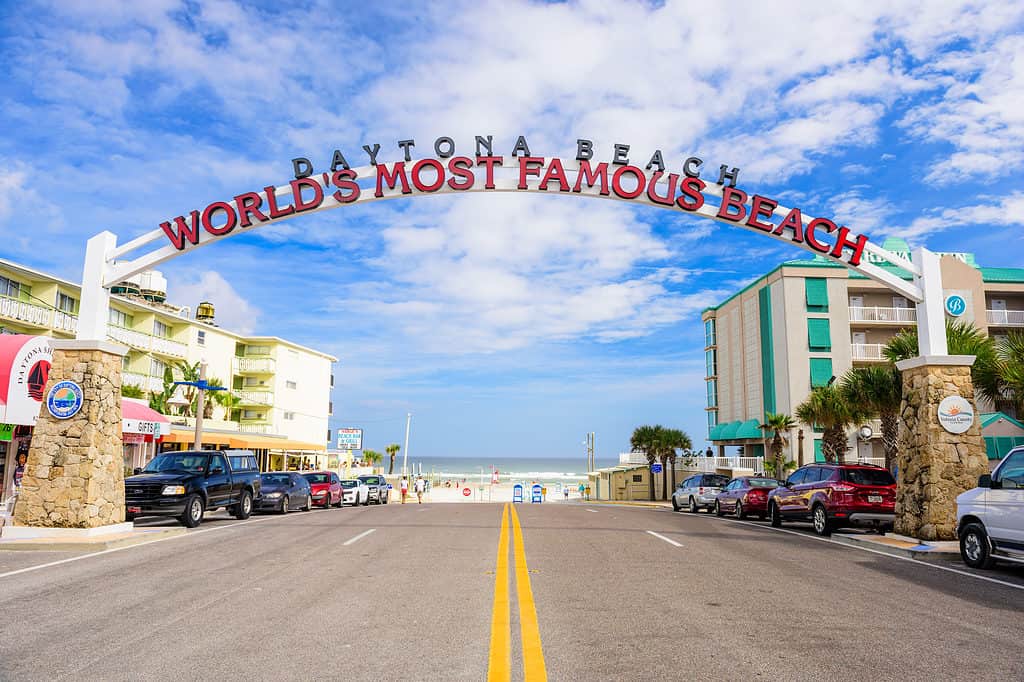 Daytona Beach, FL, USA - February 2, 2015: Beachgoers in the distance walk below the Daytona Beach welcome sign. The popular spring break destination is dubbed "World's Most Famous Beach."