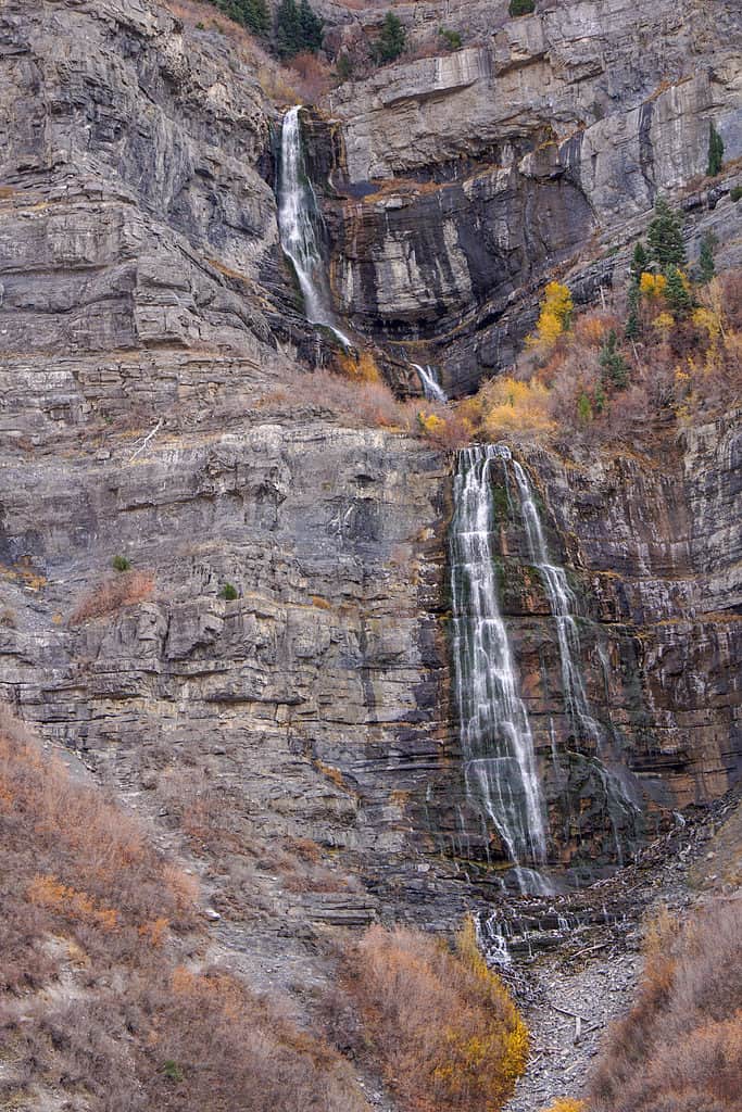 Fall View of Bridal Veil Water Falls Utah Provo Canyon. The fall is visible vertically in the center frame. It appears as two separate tiers. the upper tier is singular, while the lower tier is double cascade. surrounded by rock and dry, brown-to-gold vegetation