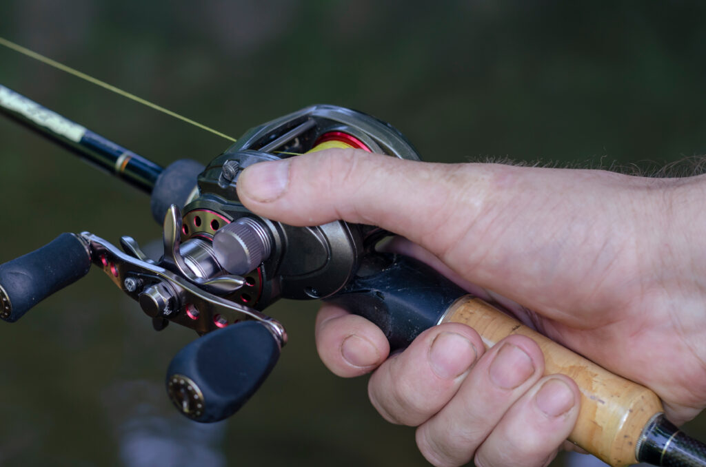 Close-up of a man's hand with bait casting rods. Caucasian man holding a fishing rod with a baitcasting reel.