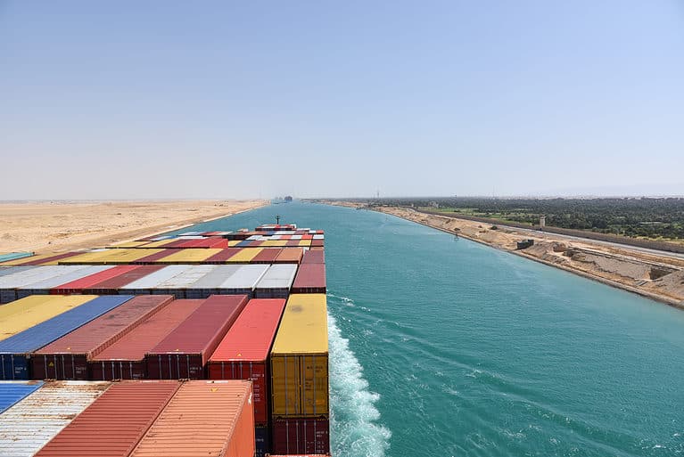 View on the containers loaded on deck of cargo ship. Vessel is transiting Suez Canal on her international trade route. Suez canal landscape.