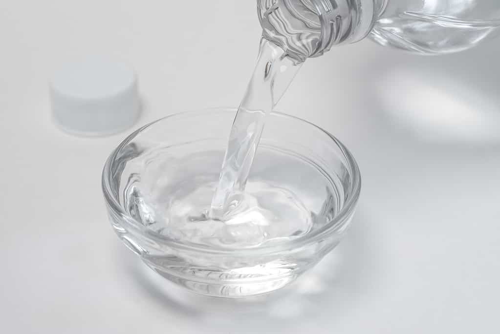 Vinegar being poured from a bottle into a glass bowl