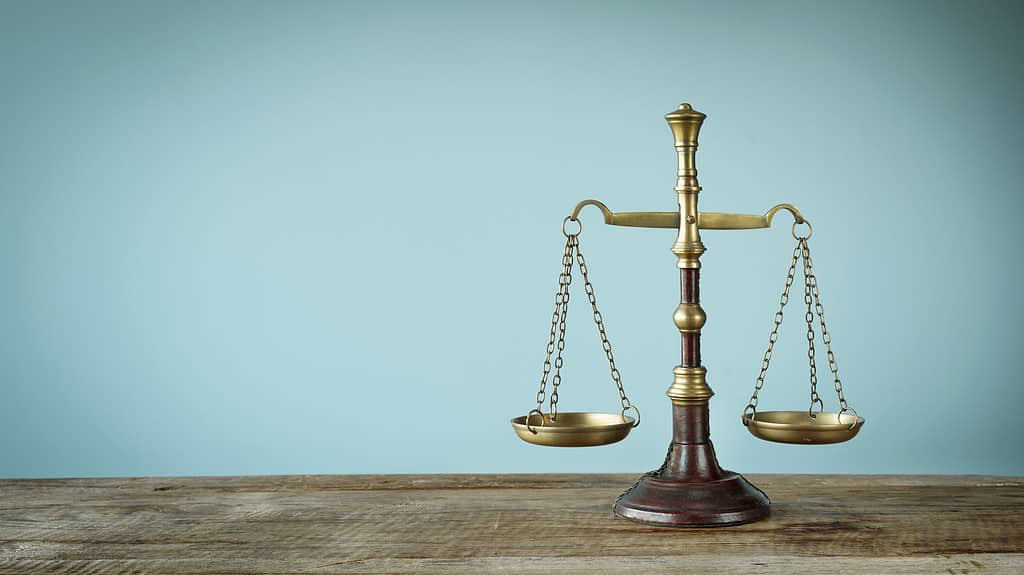 Balance scale on wooden desk, turquoise background