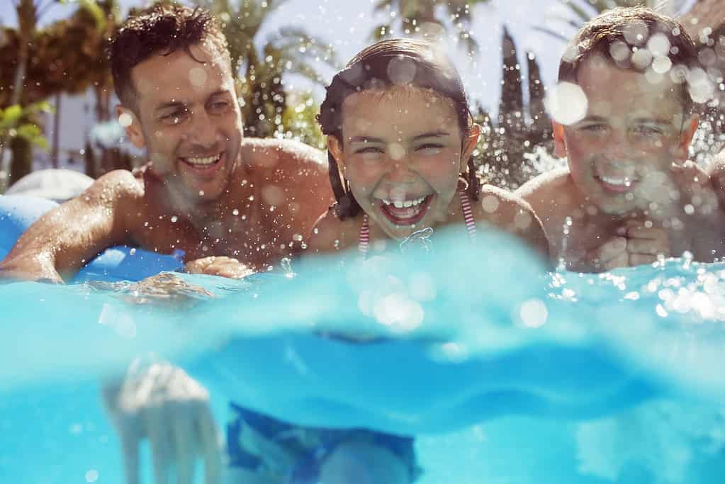 Two kids and an adult swimming in water