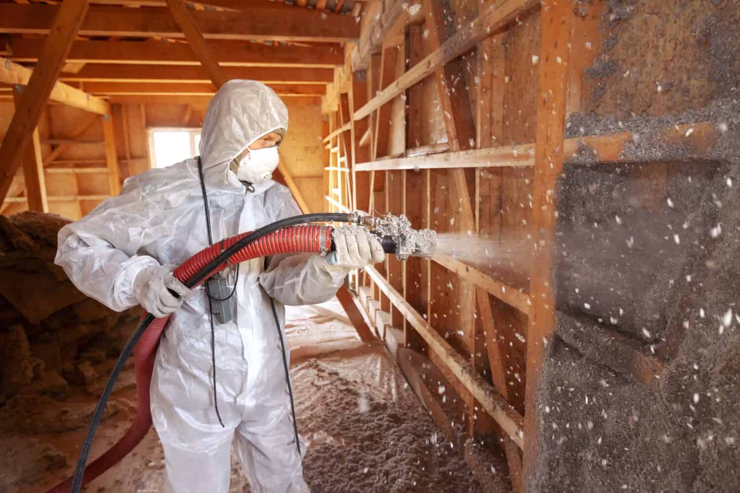 Spraying cellulose insulation on the wall