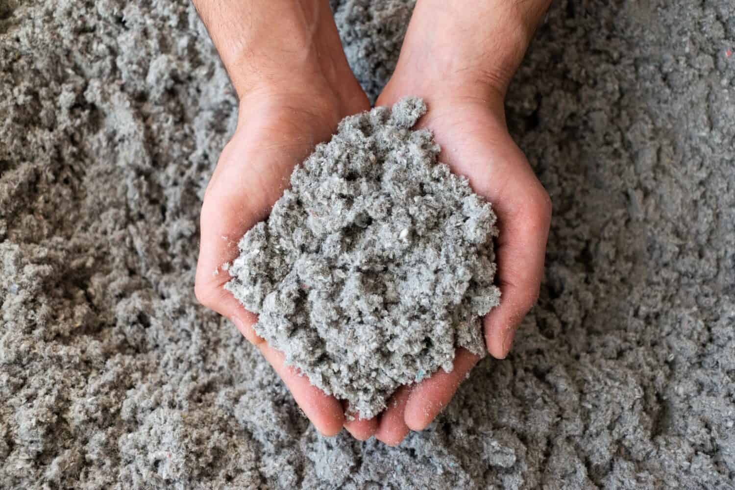 Close shot of eco friendly cellulose insulation filling held in hand 